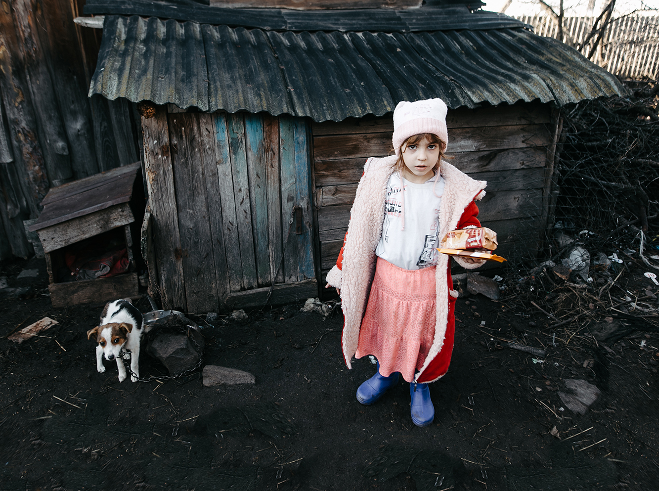 Neyla fra Ukraine, står udenfor deres slidte hus, med lidt julegodter i hånden.